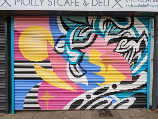 Shutters sprayed with an artwork of colourful geometric shapes and black and white leaves