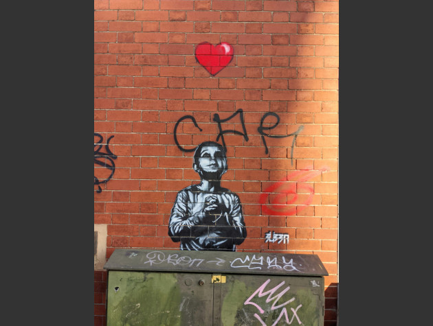 Small black-and-white stencil of a boy looking up at a red heart