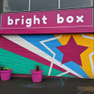 Painted shop shutters in bright colours with geometric shapes, dominated by a giant 5-point star on the right hand side