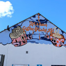 Close-up of mural featuring two cups with faces and the words 'Let's have coffee and cake kid'