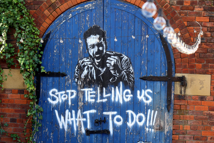 Black and white mural of a man shouting with the words 'Stop telling us what to do'