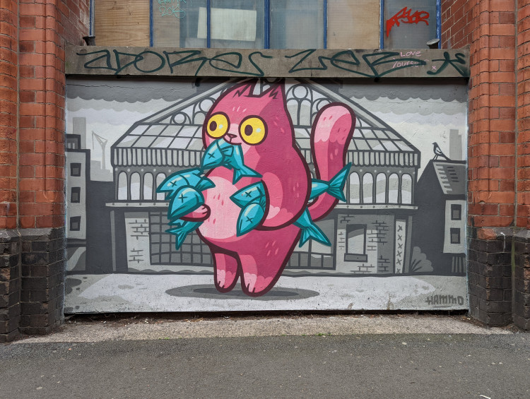 Mural of a pink cartoon cat holding fish in its paws and one in its mouth