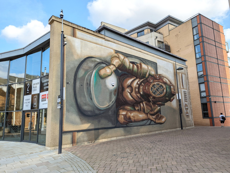 Large wall mural of a deep sea diver climbing out of a washing machine