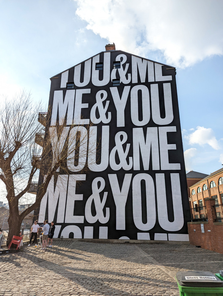 Tall wall mural with the writing You & Me, Me & You repeated across it
