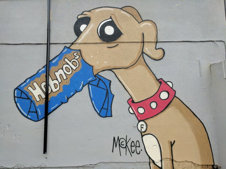 Mural of a guilty looking grey hound with its muzzle in a packet of Hobnobs