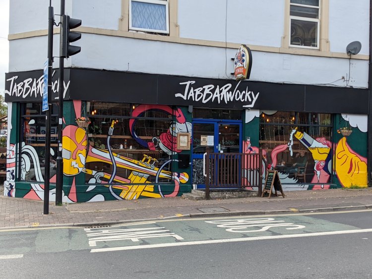 Colourful mural featuring a saxophone player, a woman playing an unspecified woodwind instrument and abstract shapes in bold reds, greens, pinks and blacks, with text including 'The dreamers' and 'Rhythm'