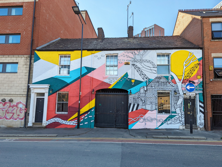 Mural on the facade of APG Works depicting an urban landscape and a bold geometric design