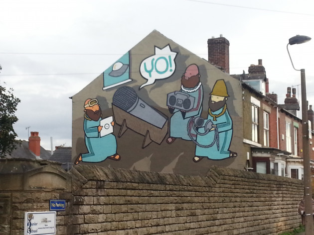 Large gable end mural featuring three wisemen surrounding a microphone in a manger saying 'yo'