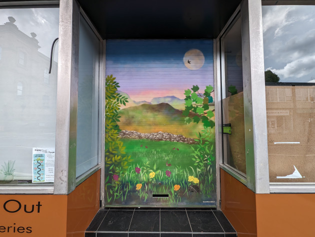 Store shutter painted with a countryside scene