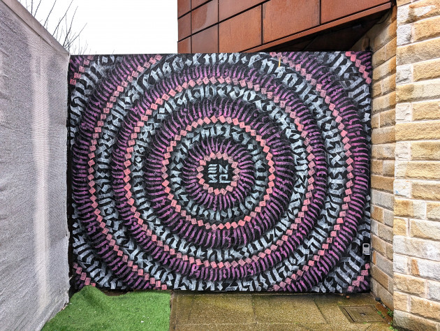Mural of rings consisting of calligraphy style marks around the artist's name, Enso