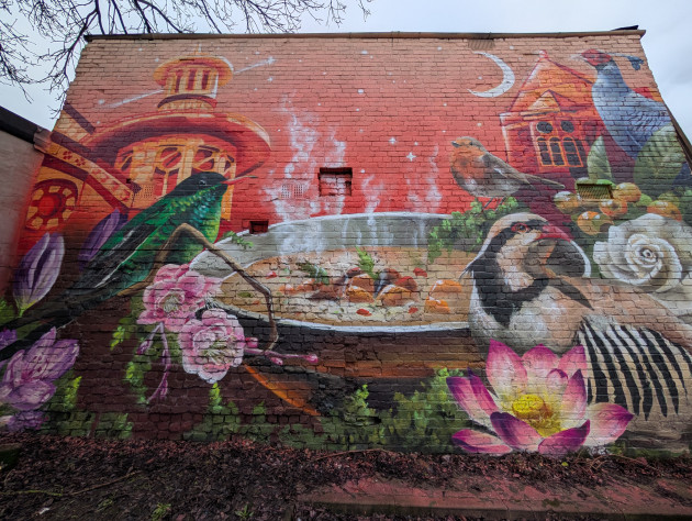 Mural featuring birds from around the world perched around a bowl of curry, buildings from London Road feature in the background