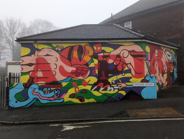 Colourful mural featuring various imagery including many hands and the word Aspire written across it