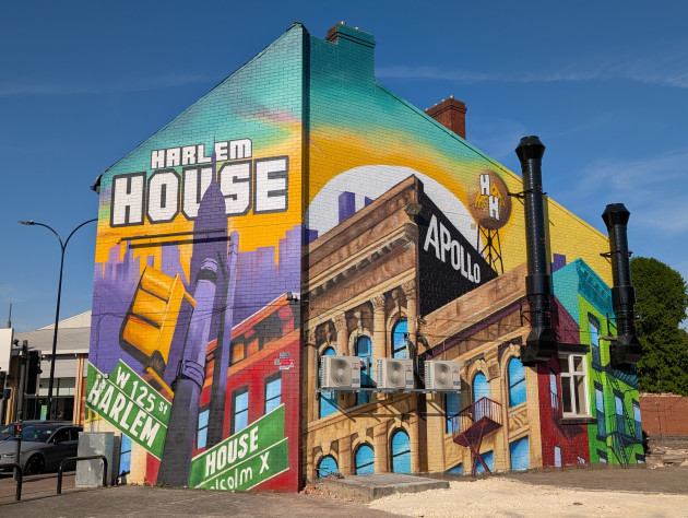 Large mural on the side of a former pub featuring a Harlem landscape complete with traffic lights