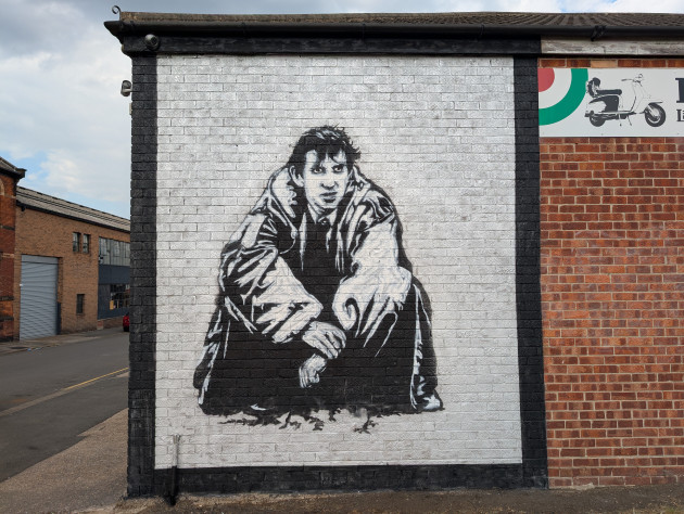 Black and white stencil mural of Phil Daniels as Jimmy from Quadrophenia sat crouched down in a large parka coat