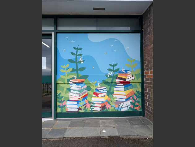 Mural featuring stacks of books amongst tall green plants, small human-shaped figures sit on top of the books and leaves reading books