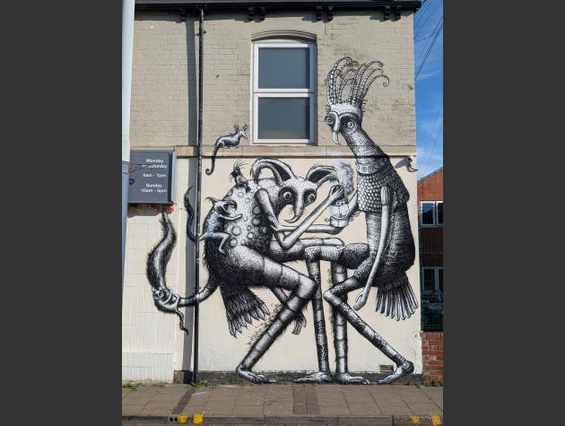 Black and white illustrative mural on the side of a building featuring various mystical creatures