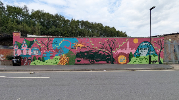 Long wall mural featuring a classic 1950's car illustration in the centre next to a large number 57, the background features a silhoutted factory