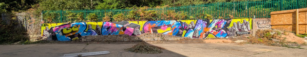 Wide graffiti mural by R U OK stretched across a low wall