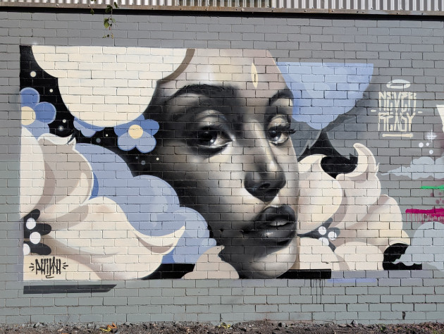 Mural of a womans face surrounded by cloud like flowers