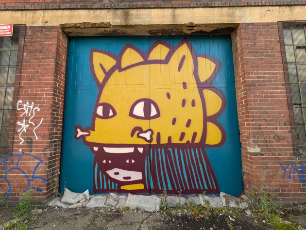 Mural of a masked woman wearing a creature with bone through its nose as a hat
