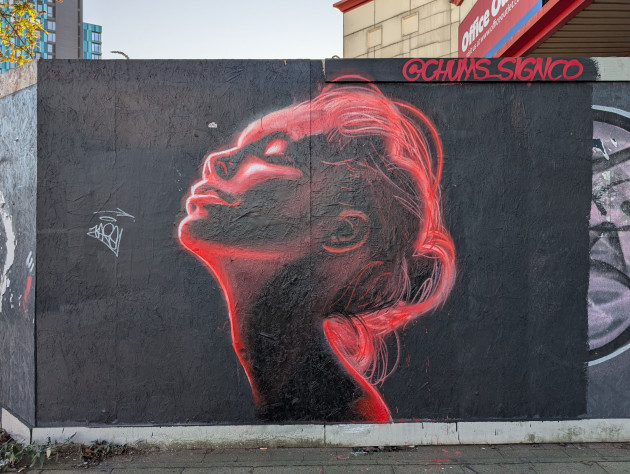 Graffiti art of a serene side profile of a woman with closed eyes, looking upward, the figure is illuminated with glowing red and white highlights that trace the contours of the face, neck and loosely tied hair