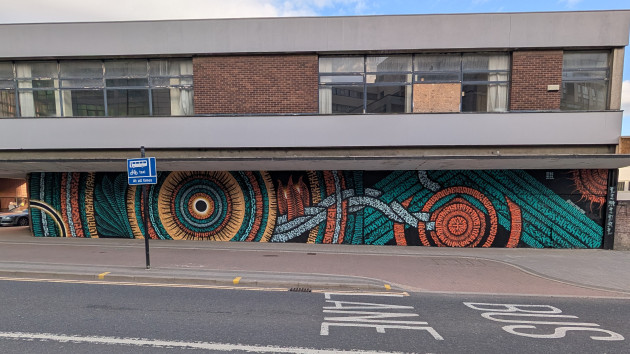 Wide Enso mural formed of geometric shapes made up of calligraphy style patterns