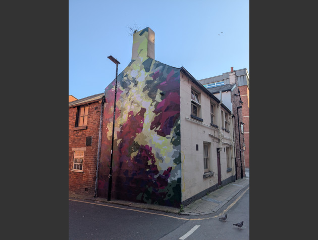 Abstract mural depicting a view looking up through a canopy of trees with light filtering and refracting through green and purple leaves