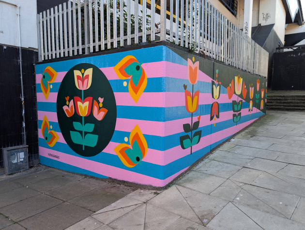 Abstract floral mural featuring colourful tulip like flowers on a blue and pink striped background