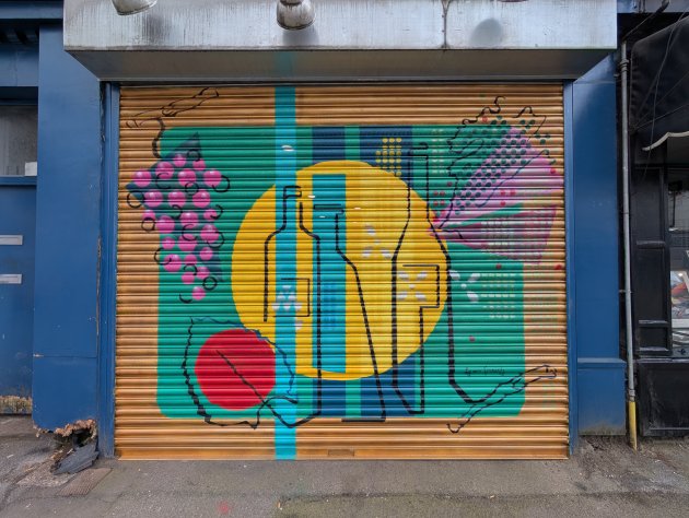 Abstract artwork on shop shutters featuring outlines of wine bottles and some red grapes