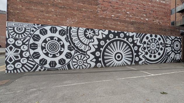 Long black and white mural made up of geometric circular and cog shapes