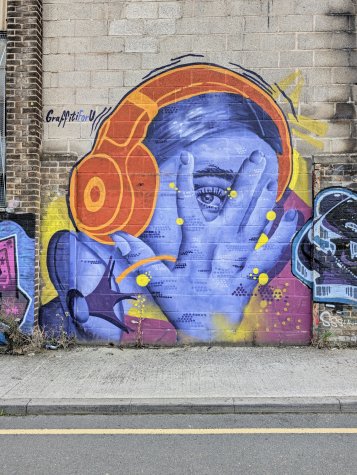 Mural of a girl wearing big headphones, hand covering her face