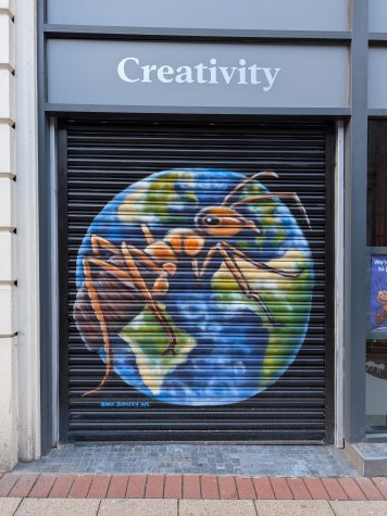Shutters painted with a giant ant in front of the world