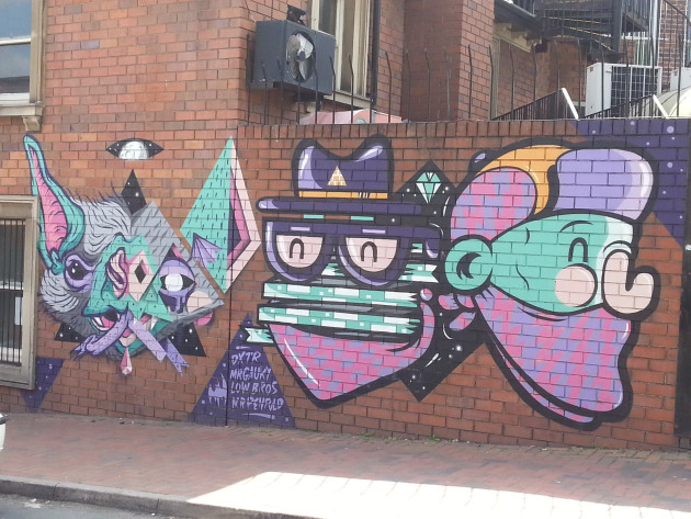 Mural of three different faces in various graffiti styles