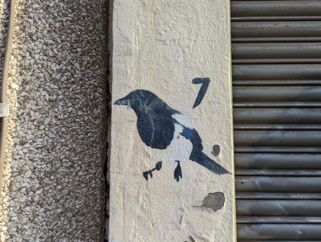 Small mural of a magpie with a zipped beak and the number 7