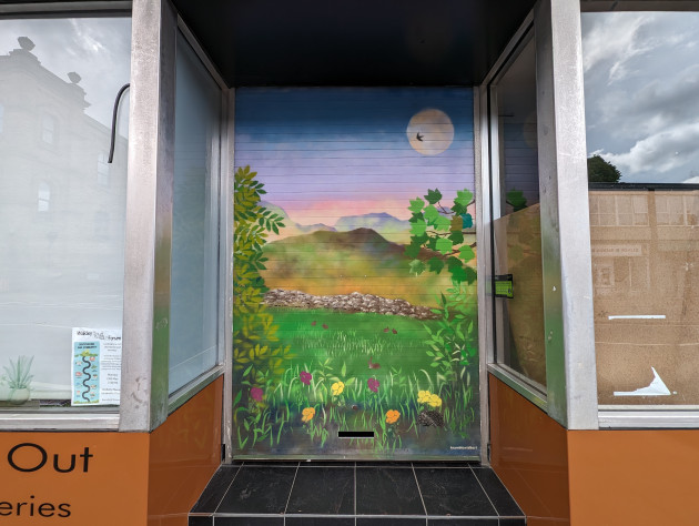 Store shutter painted with a countryside scene