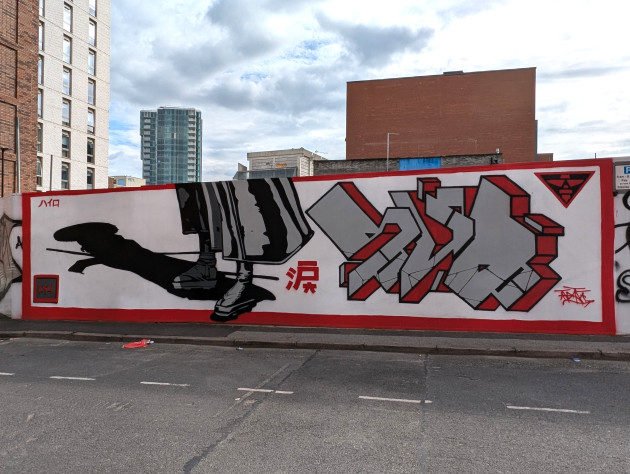 Mural of some feet and the bottom of a kimono with an outstretch shadow of a samurai