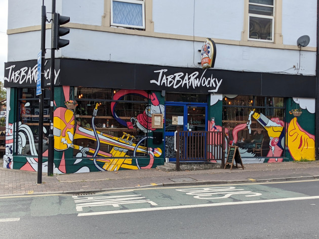 Mural featuring instruments and drinks covering a bar's facade including the glass windows