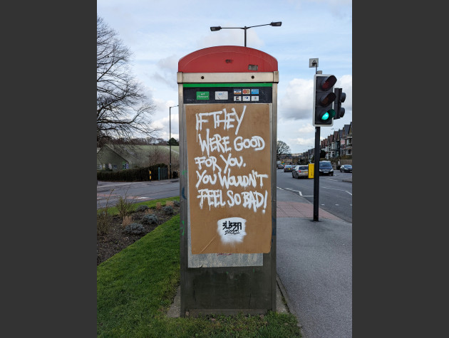 Paste-up on the side of a phonebox with the words 'If they were good for you, you wouldn't feel so bad!'
