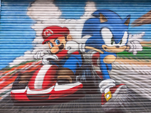 Shop shutters painted with Mario racing Sonic the Hedgehog, Mario is in a racing kart