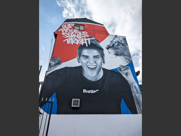 Black and white mural of Millie Bright in a celebratary pose in front of the Pepsi logo with the words Our Pride Shines bright
