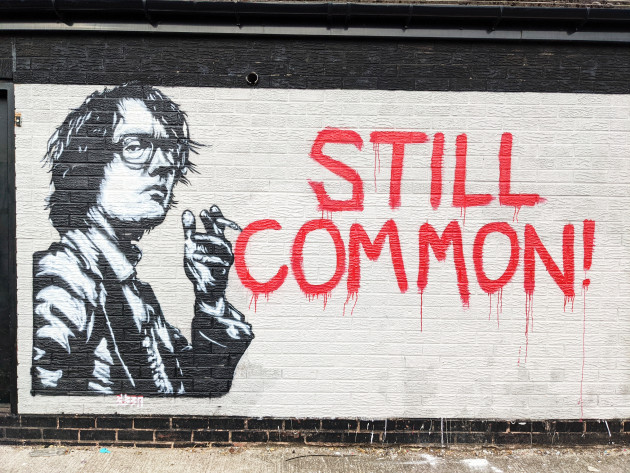 Stencil mural of Jarvis Cocker next to the spray painted words 'Still Common'