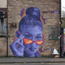 mural of a woman peering over the top of her sunglasses, hair tied into a tight bun