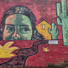 mural featuring the top part of a face peering out over a red desert landscape featuring cacti