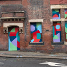 Further detail of the vibrant, abstract geometric artwork covering the boarded up windows and doors of the Citadel