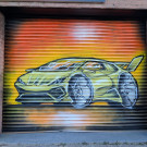 Graffiti mural on a metal roller shutter featuring a bright yellow Lamborghini supercar