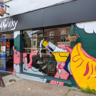 Mural of a man drinking a beer from a bottle with his tounge sticking out