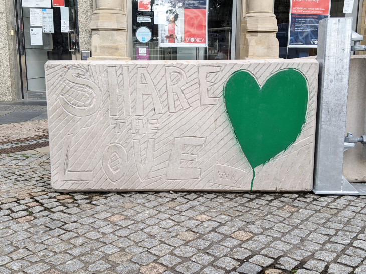 Concrete block with the phrase Share the Love carved into it with a heart shape painted green